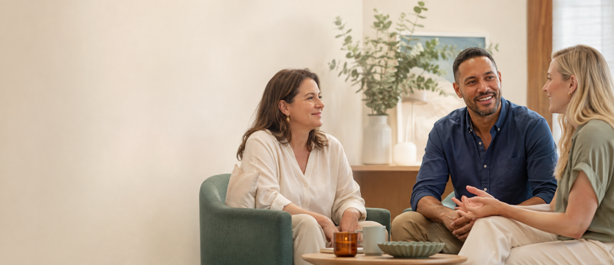 Three psychology professionals in conversation in a warm consulting room